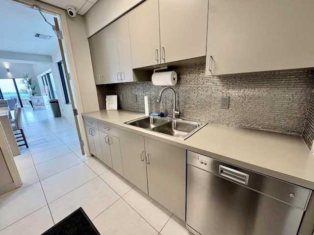 kitchen with dishwasher, backsplash, sink, light tile patterned floors, and white cabinetry