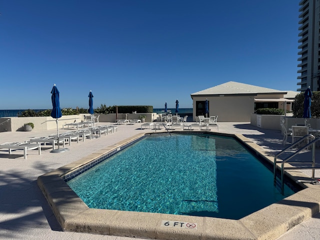 view of pool with a patio and a water view