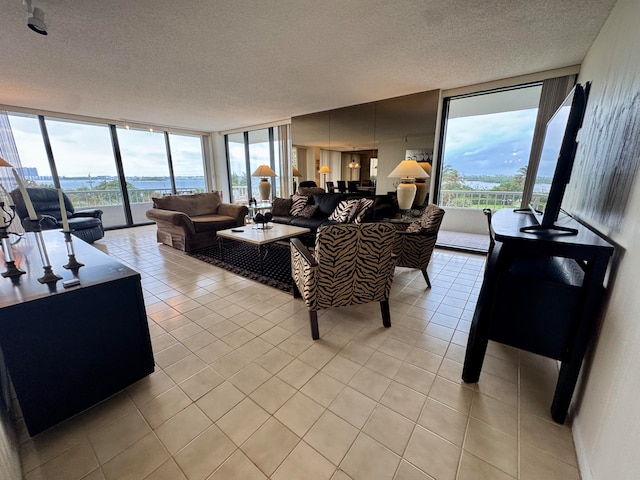 tiled living room with a textured ceiling, a water view, and expansive windows