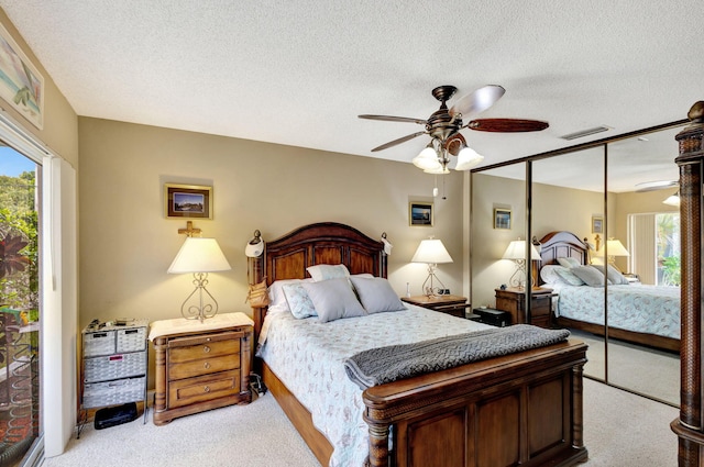 bedroom featuring a textured ceiling, ceiling fan, light carpet, and a closet