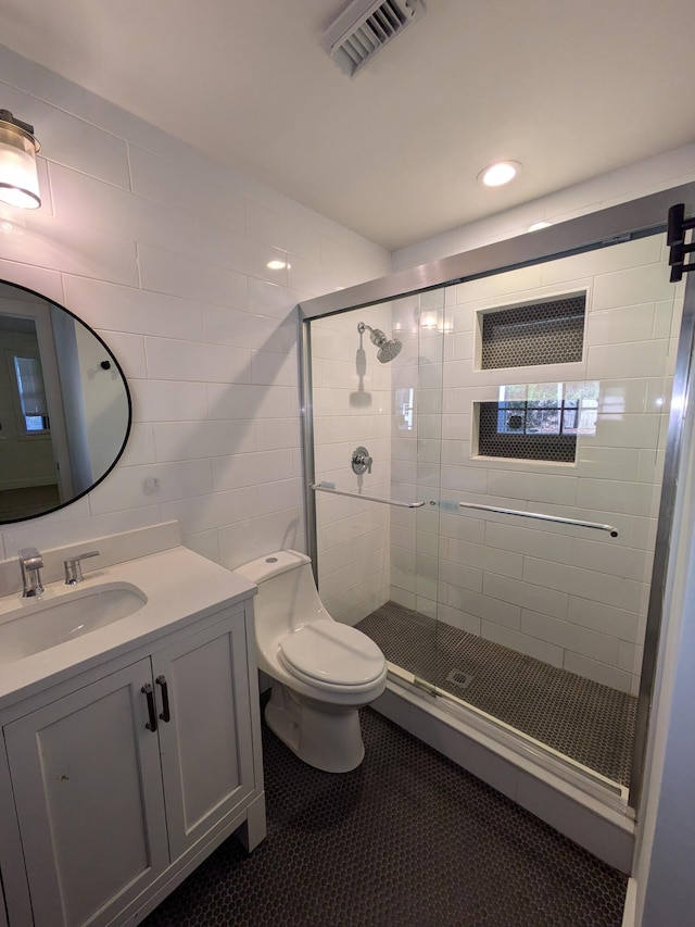 bathroom featuring toilet, vanity, tile walls, and walk in shower