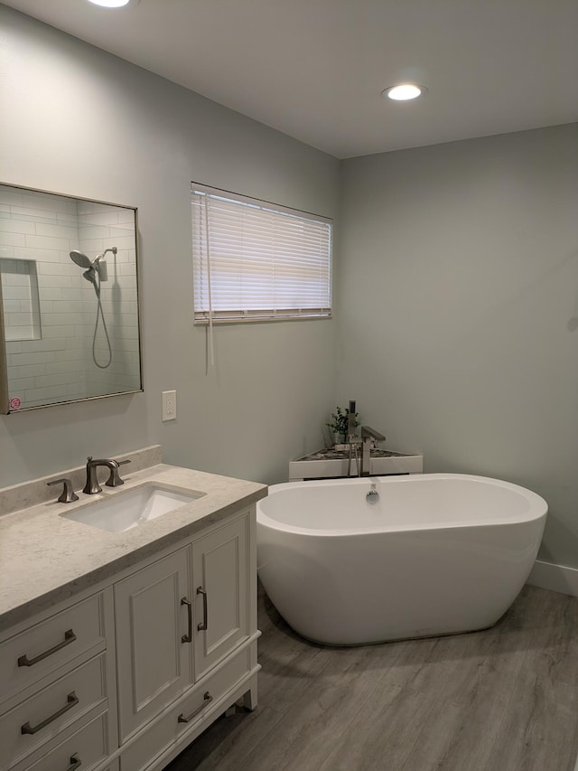 bathroom with plus walk in shower, hardwood / wood-style floors, and vanity