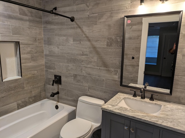 full bathroom featuring vanity, tiled shower / bath combo, toilet, and tile walls