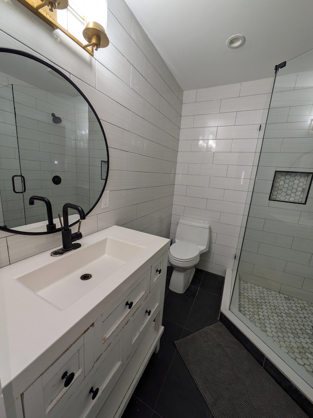 bathroom with tile patterned floors, walk in shower, vanity, tile walls, and toilet