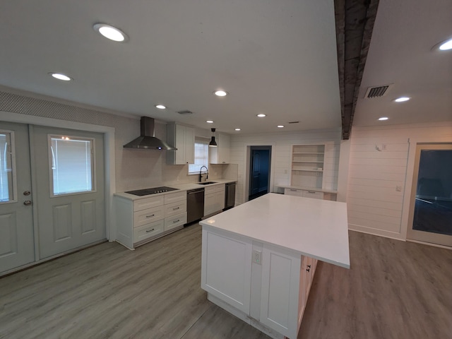 kitchen featuring sink, black appliances, wall chimney range hood, light hardwood / wood-style floors, and white cabinetry