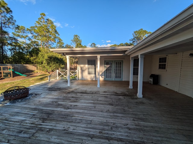 deck featuring a playground, french doors, and a fire pit