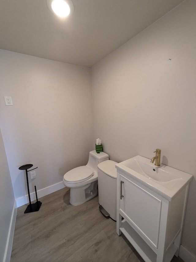 bathroom with toilet, vanity, and hardwood / wood-style flooring