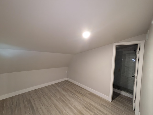 bonus room with lofted ceiling and light wood-type flooring