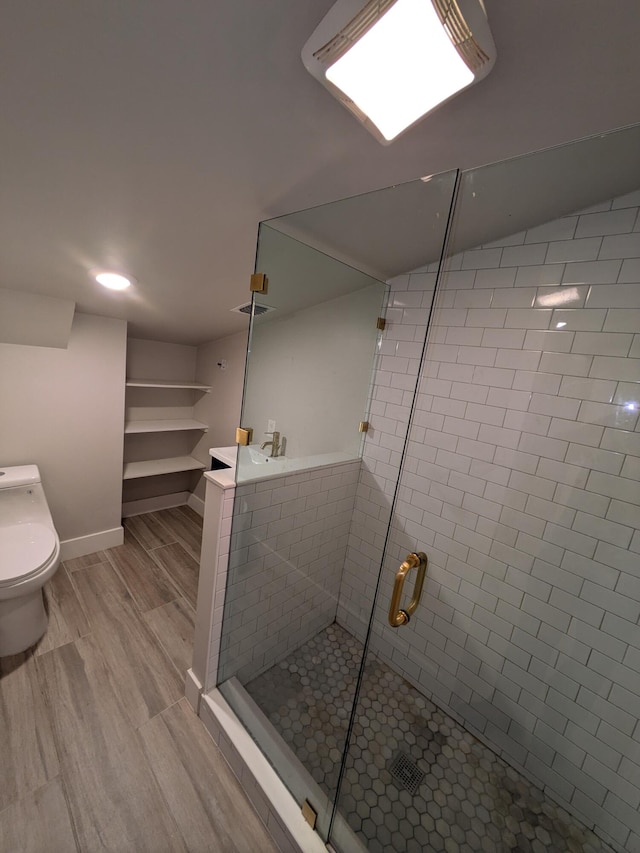 bathroom featuring toilet, a shower with door, and hardwood / wood-style flooring