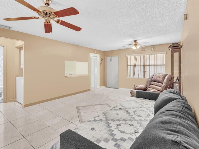 living room with ceiling fan, light tile patterned floors, and a textured ceiling