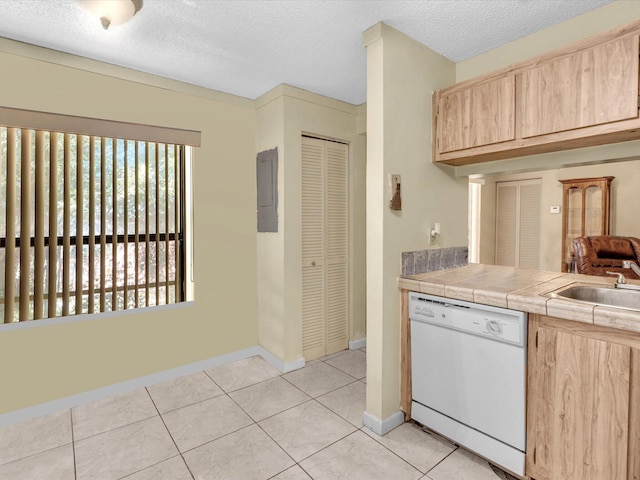 kitchen with light brown cabinetry, dishwasher, light tile patterned floors, and a textured ceiling