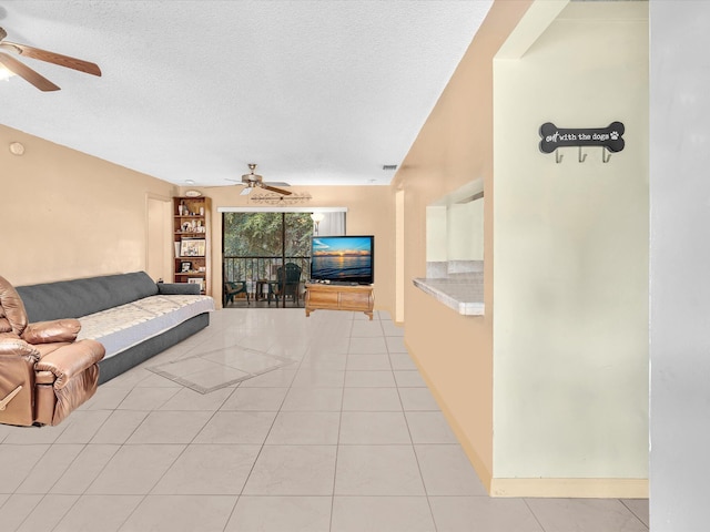 living room featuring a textured ceiling, ceiling fan, and light tile patterned flooring