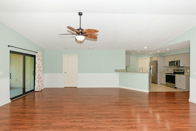 unfurnished living room featuring ceiling fan, sink, vaulted ceiling, and hardwood / wood-style flooring