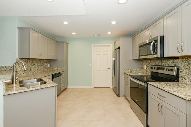 kitchen featuring gray cabinetry, light stone counters, sink, and appliances with stainless steel finishes