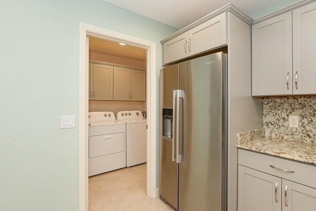 kitchen with decorative backsplash, light stone counters, separate washer and dryer, and stainless steel refrigerator with ice dispenser