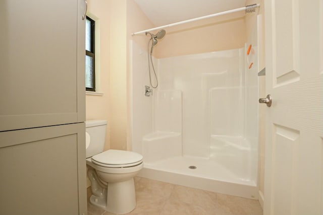 bathroom featuring tile patterned flooring, toilet, and walk in shower