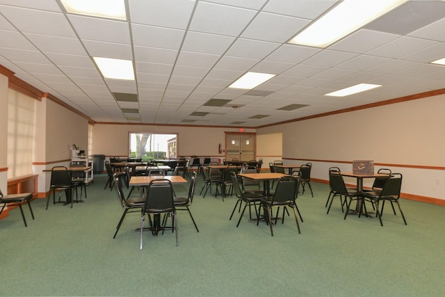 carpeted dining area featuring crown molding and a drop ceiling