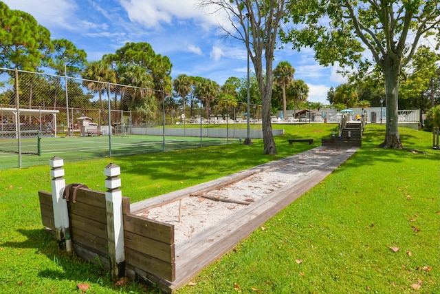 view of property's community featuring a lawn and tennis court