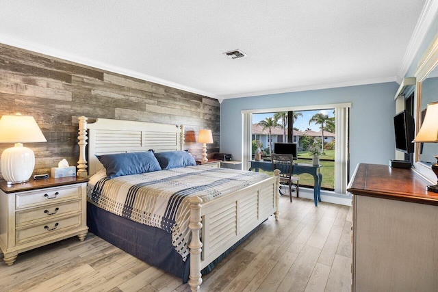 bedroom with a textured ceiling, light hardwood / wood-style floors, crown molding, and wood walls