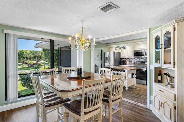 dining area featuring a chandelier, a textured ceiling, and dark hardwood / wood-style flooring