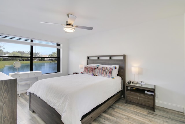 bedroom with ceiling fan, a water view, and hardwood / wood-style flooring