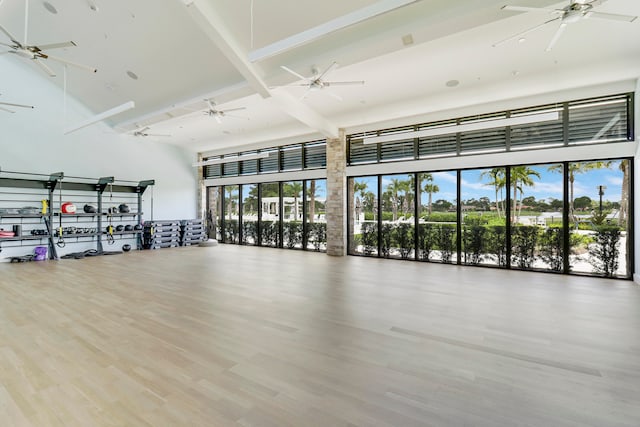 exercise room featuring wood-type flooring and a towering ceiling