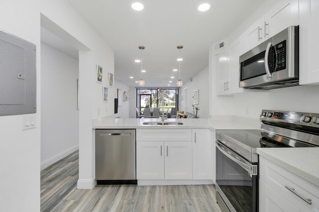 kitchen featuring white cabinets, sink, light wood-type flooring, kitchen peninsula, and stainless steel appliances