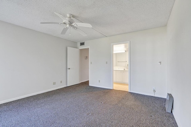 unfurnished bedroom featuring ensuite bath, ceiling fan, a textured ceiling, and dark colored carpet