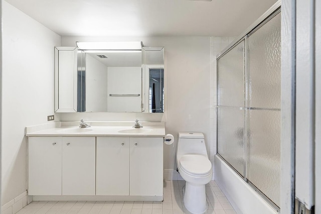 full bathroom with shower / bath combination with glass door, vanity, tile patterned flooring, and toilet