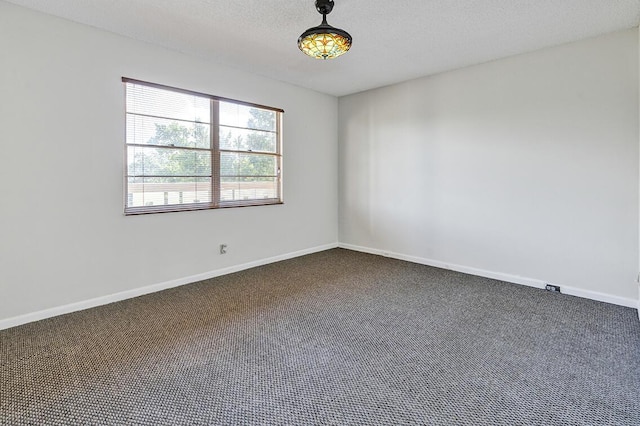 spare room with a textured ceiling and dark carpet