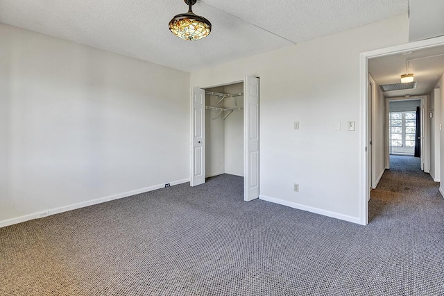 unfurnished bedroom with dark colored carpet, a textured ceiling, and a closet