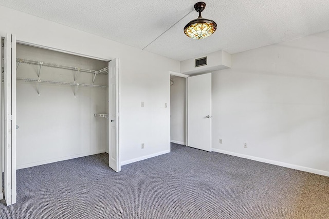 unfurnished bedroom featuring dark colored carpet, a textured ceiling, and a closet