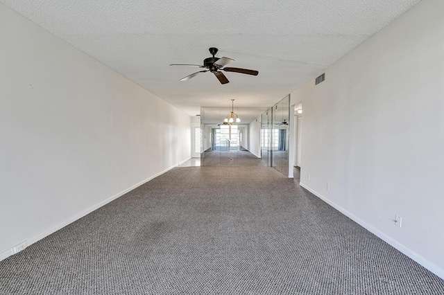 empty room with ceiling fan with notable chandelier and a textured ceiling