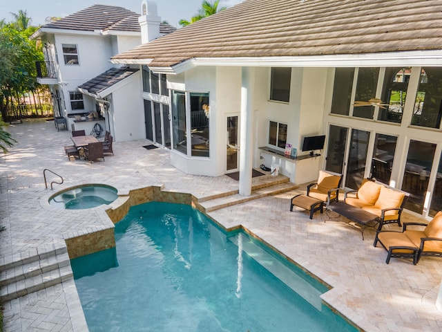 rear view of house with a patio area and a pool with hot tub