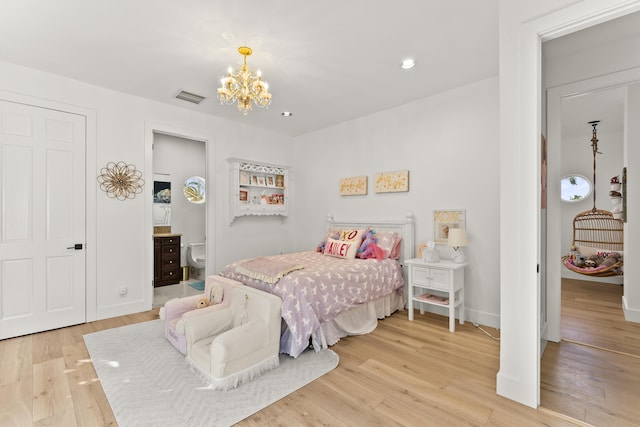 bedroom with connected bathroom, a notable chandelier, and light hardwood / wood-style floors