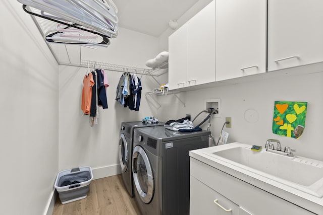 laundry room featuring cabinets, separate washer and dryer, sink, and light hardwood / wood-style floors