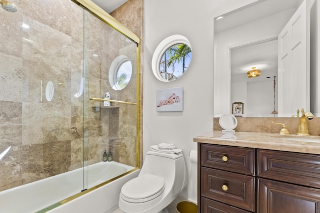 full bathroom featuring vanity, shower / bath combination with glass door, and toilet