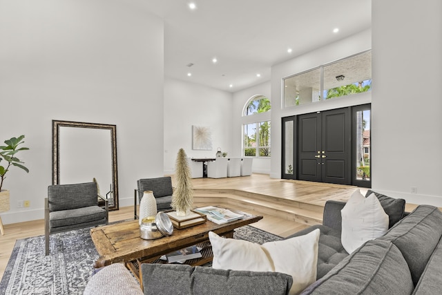 living room with a healthy amount of sunlight, light hardwood / wood-style flooring, and a high ceiling