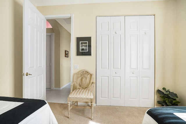 bedroom with light carpet, light tile patterned floors, arched walkways, and a closet