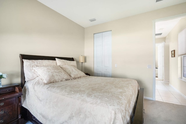 bedroom with light carpet, light tile patterned floors, baseboards, vaulted ceiling, and a closet