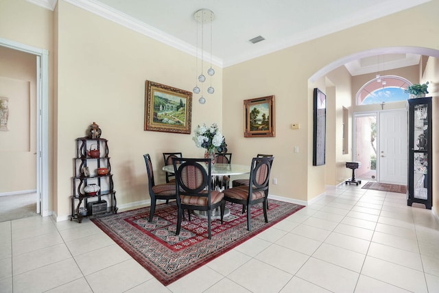 dining area with arched walkways, visible vents, ornamental molding, light tile patterned flooring, and baseboards