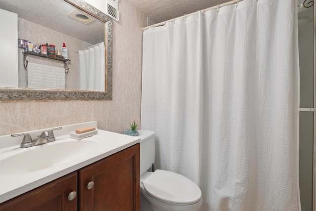 bathroom with vanity, toilet, and a textured ceiling