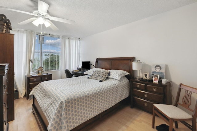 bedroom featuring ceiling fan, light wood-type flooring, and a textured ceiling