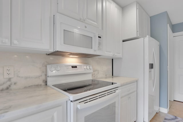 kitchen with white appliances, tasteful backsplash, light tile patterned flooring, light stone counters, and white cabinetry