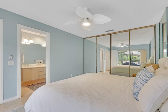 tiled bedroom featuring ceiling fan, sink, ensuite bathroom, and a closet