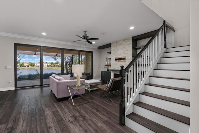 living room featuring dark hardwood / wood-style floors, ceiling fan, crown molding, and a fireplace