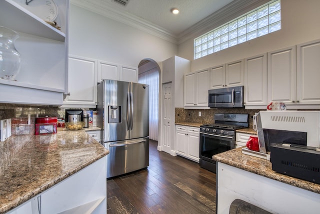 kitchen with stone counters, white cabinetry, appliances with stainless steel finishes, and a towering ceiling