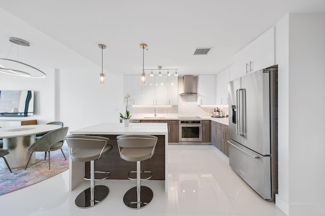 kitchen with appliances with stainless steel finishes, backsplash, light tile patterned floors, pendant lighting, and white cabinets