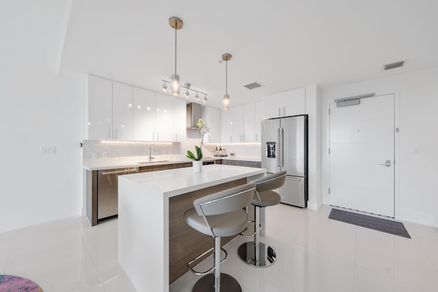 kitchen with white cabinetry, sink, wall chimney range hood, and appliances with stainless steel finishes