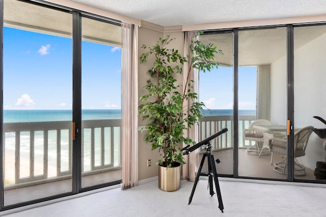 interior space with a beach view, a textured ceiling, and a water view